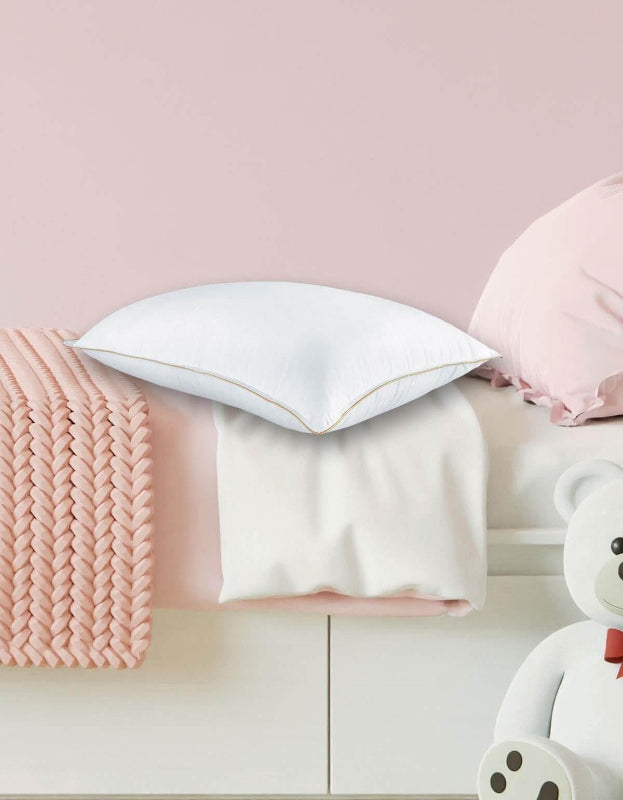 Weißes Kissen mit goldener Naht auf rosa Strickdecke, kinderfreundlich gestaltet