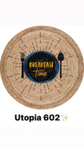 Round woven rug with 'Breakfast Time' plate, fork, and spoon design, natural and black colors.